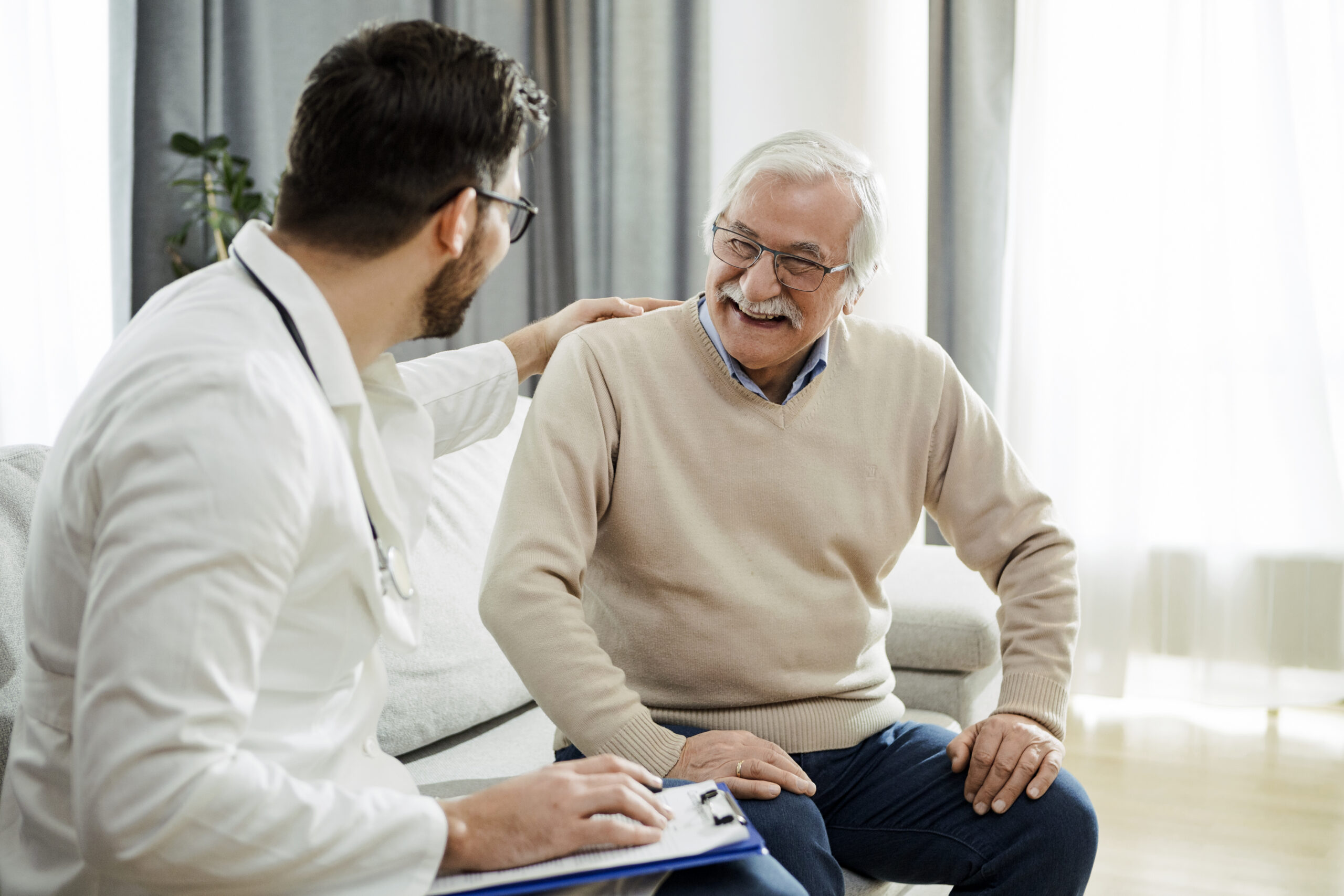 Junger Doktor auf der Couch Junger Arzt und älterer Mann haben eine Konversation auf der Couch.