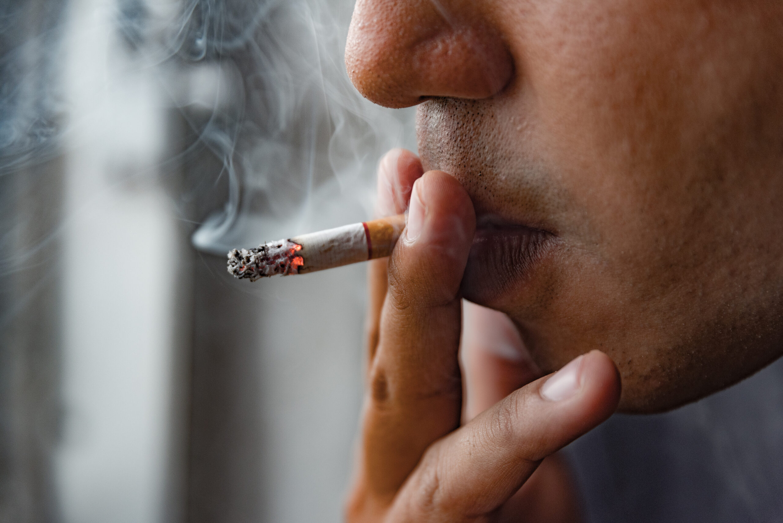 Close up male hand holding cigarette.