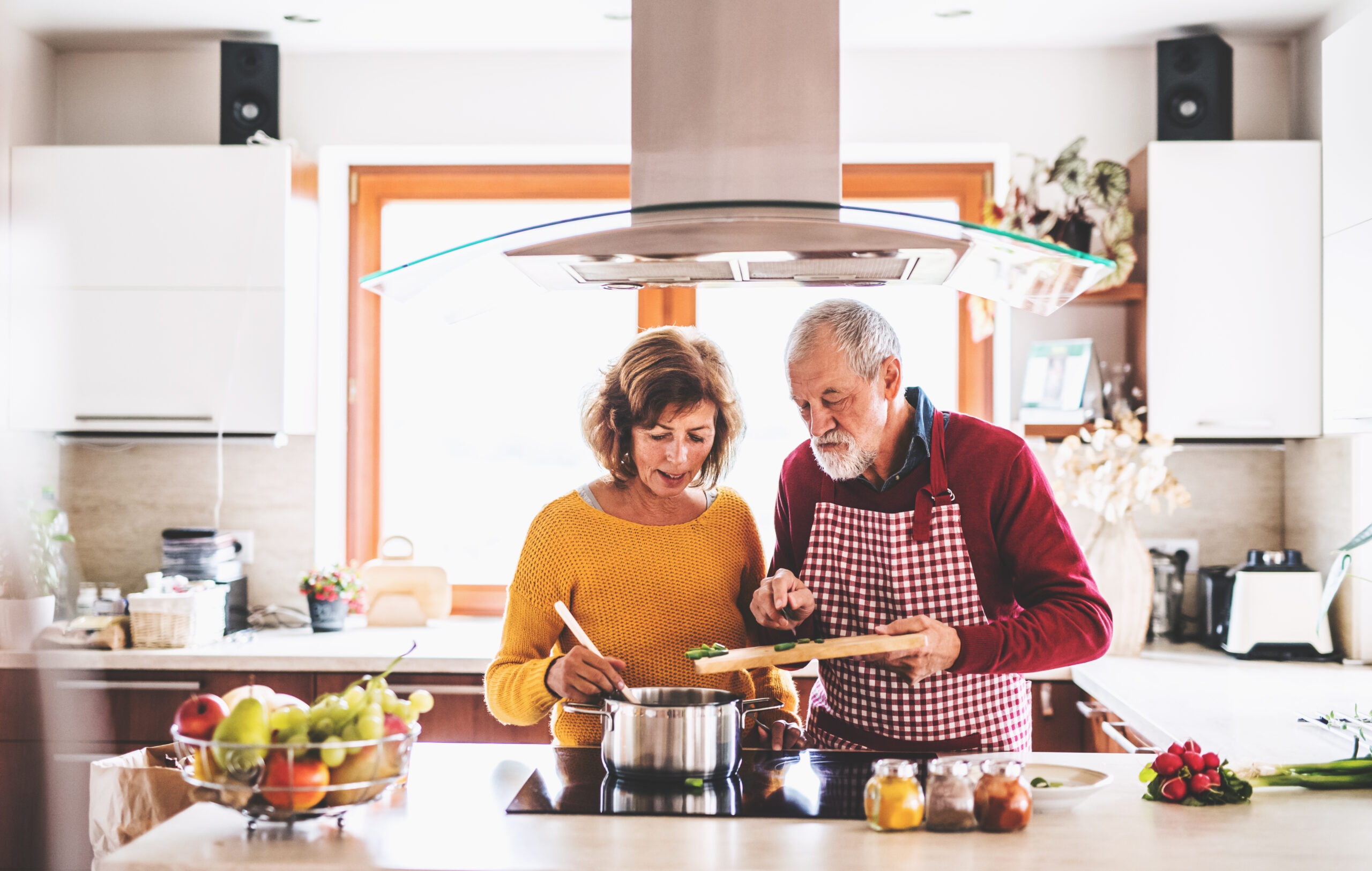 Seniorenehepaar kocht gemeinasam gesund und reichhaltich in ihrer Küche daheim.
